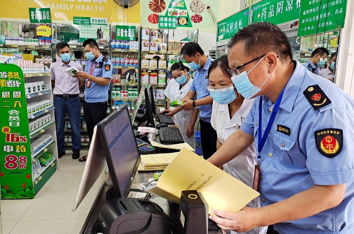 图为6月20日，该局执法人员正在一家零售药店检查销售退烧、止咳、抗病毒、抗菌类药品实名登记和信息报告情况。